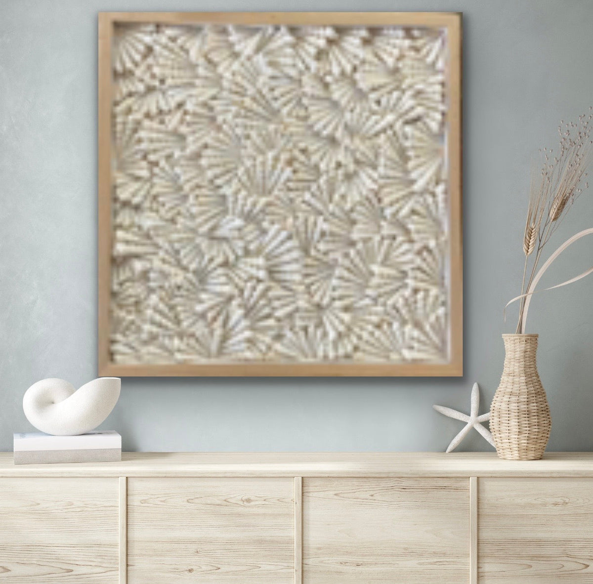 Turritella shell wall art in natural wood frame displayed above sideboard